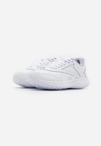 Paire de baskets blanches de sport avec lacets, semelle texturée et détails en mesh, sur fond blanc, inclinées vers la droite.
