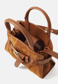 Sac à main en cuir suédé et en cuir marron avec deux poignées courtes, quincaillerie dorée et détail à nœud à l'avant. L'intérieur présente un compartiment spacieux.