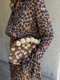 Kopertówka z koralików o brązowej podstawie i kremowych akcentach, z teksturowanym wzorem i okrągłymi, kremowymi ozdobami z koralików na wierzchu.