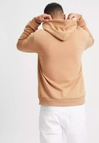 Beżowa bluza z kapturem, z długimi rękawami i luźnym krojem. Z tyłu widoczny jest regulowany kaptur oraz szczegóły ściągacza.