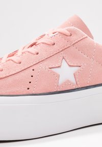 Baskets en daim rose blush avec un emblème d'étoile blanche, une semelle en caoutchouc blanche plate et des coutures contrastées. Caractérisées par un bout arrondi et un design à lacets.