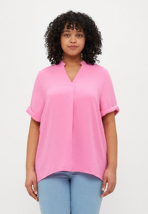 Pink short-sleeve blouse with a V-neck, textured fabric, and rolled cuffs. Features a relaxed fit and curved hemline.