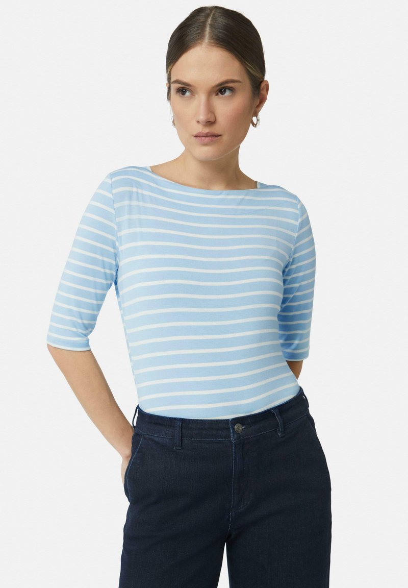 Lichtblauw gestreept topje met driekwartmouwen, gemaakt van zachte stof, gecombineerd met donkere jeans. Eenvoudige halslijn, casual stijl.