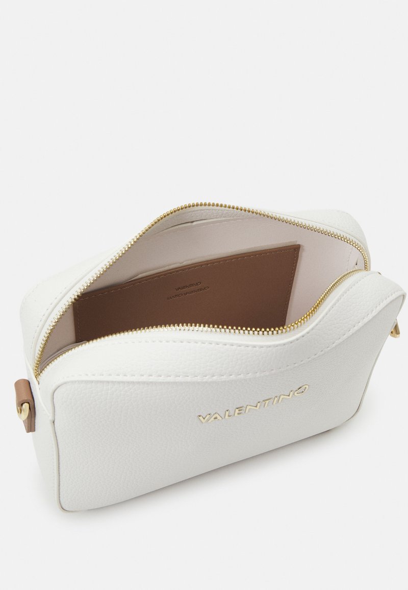 Bolso de cuero blanco texturizado con cierre de cremallera, que presenta un interior marrón y detalles del logo en dorado en la parte delantera.