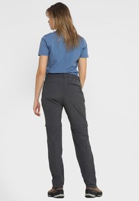 Pantalones de senderismo grises con piernas desmontables, cinturilla ajustada y material duradero, combinados con una camiseta de manga corta azul y zapatos de exterior.