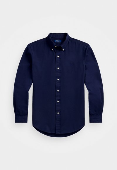 Camisa azul-marinho de botões com mangas longas, colarinho clássico e botões brancos à frente; logotipo subtil no peito. Material em algodão.