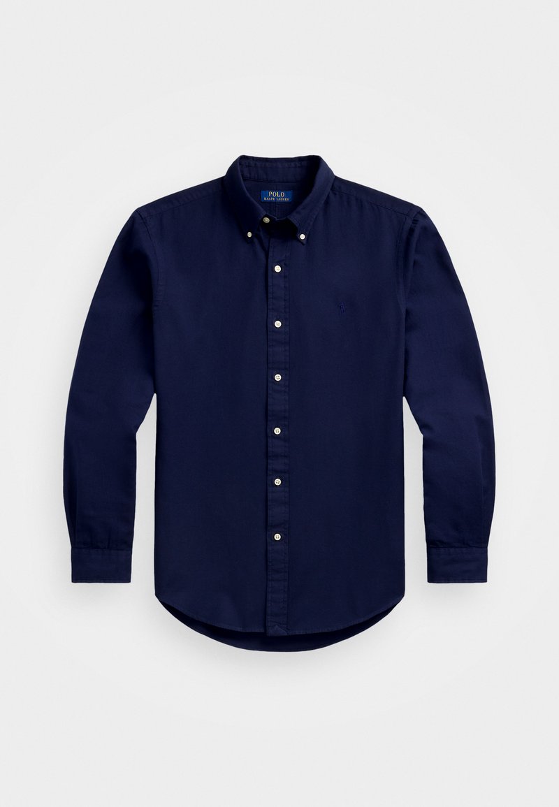 Ναυτικό μπλε πουκάμισο με κουμπιά και μακριά μανίκια, κλασικό γιακά και λευκά κουμπιά μπροστά; διακριτό λογότυπο στο στήθος. Υλικό από βαμβάκι.