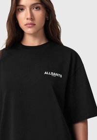 T-shirt oversize nera in cotone, con il logo bianco "ALLSAINTS LONDON" sul lato sinistro, con maniche corte e scollatura rotonda.