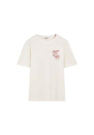Camiseta de algodón color crema con un corte holgado, que presenta un texto gráfico rojo "SCALPERS GAME" y un estampado de dados en el área del pecho izquierdo.