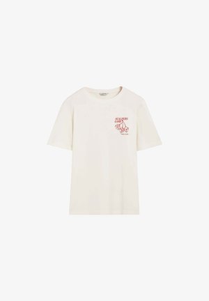 Camiseta de algodón color crema con un corte holgado, que presenta un texto gráfico rojo "SCALPERS GAME" y un estampado de dados en el área del pecho izquierdo.