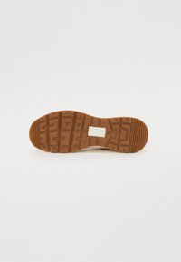 Rubber sole with a textured, patterned design in brown. Smooth white upper with minimal detailing, suitable for casual wear.