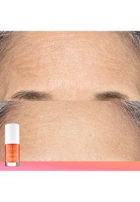 Butelka serum C.E.O. umieszczona obok poddanej zabiegowi skóry; gładka, lekko lśniąca tekstura z minimalnymi zmarszczkami; pomarańczowy płyn w przezroczystym pojemniku.