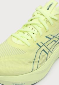 Ανοιχτό κίτρινο παπούτσι για τρέξιμο Asics με κορδόνια και μπλε λογότυπο σε πλέγμα πάνω μέρος και σόλα με τεχνολογία απορρόφησης FF Blast Max.