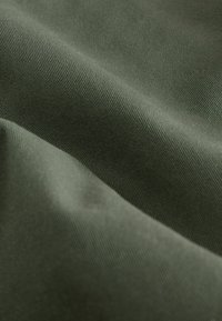 Tela de color verde oscuro con una textura suave y lisa, que presenta un sutil patrón de relieve diagonal. El material parece duradero y mate.
