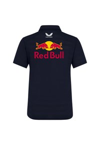 Granatowa koszulka polo z krótkim rękawem. Na plecach znajduje się logo Red Bull w kolorach czerwonym i żółtym, a także napis "Red Bull" w kolorze czerwonym. Marka Castore na kołnierzu.