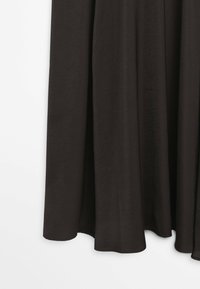 Czarna tkanina zasłony zawieszona z delikatnymi fałdami, częściowo widoczna na białym tle.