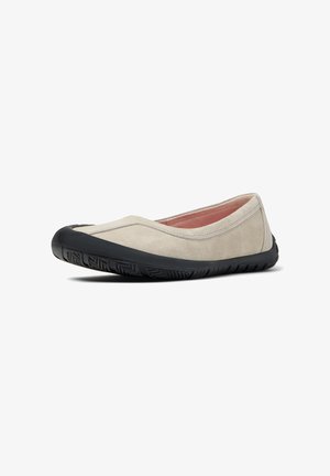 Suede beige flats with a black rubber sole, featuring a curved design, rounded toe, and minimal stitching accents. Pink inner lining visible.