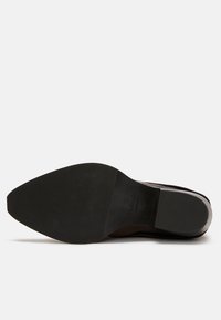 Black leather dress shoe sole featuring a smooth surface, tapered shape, and textured grip pattern; branded with manufacturer logo.