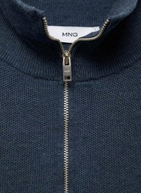 Námornícka zipsová bunda vyrobená z textúrovanej pleteniny. Obsahuje vysoký golier a strieborný zips s malým logom na ťaháku.