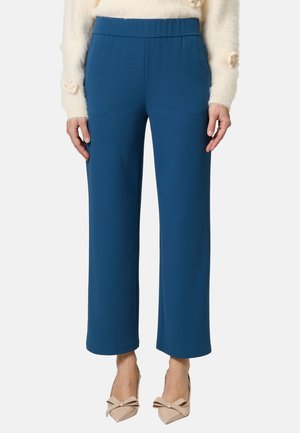 Blaue weite Hose mit elastischem Bund aus glattem Stoff. Kombiniert mit nude Farbigen High Heels mit Schleifenakzenten.