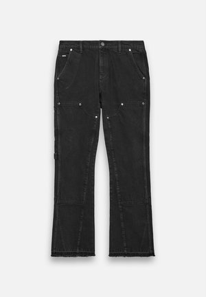 Schwarze Denim-Hosen mit geradem Bein, ausgestattet mit zwei vorderen Taschen, Metallbeschlägen und einem rohen Saumdetail am unteren Ende.