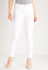 Vita denimjeans med slim fit, som har fem fickor, knäppning med knapp och en slät textur. Utanpå bärs de med ljusrosa sneakers.