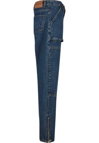 Denim pants in dark blue, featuring side pockets, a zipper detail at the ankle, and a leather patch on the waistband.