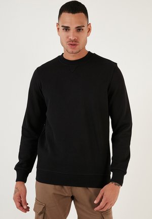 Zwarte crewneck sweatshirt gemaakt van zachte stof, met lange mouwen en geribbelde manchetten. Eenvoudig ontwerp zonder zichtbare patronen of accenten.