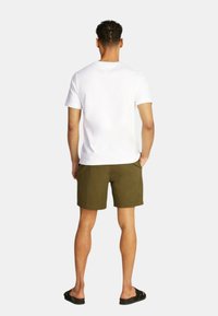 T-shirt bianca con maniche corte, abbinata a pantaloni corti verde oliva. Il tessuto sembra liscio e i pantaloni corti hanno un design semplice.
