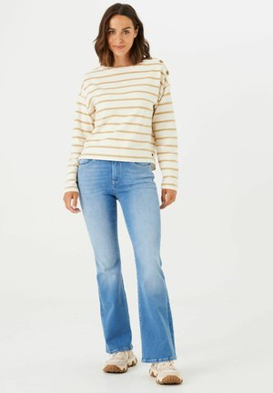 Pull à rayures à manches longues en crème et marron clair, avec un col bateau et des accents de boutons. Associé à un jean flare bleu clair.