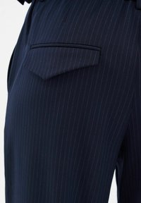 Marineblauwe broek met streepmotief en een nauwsluitende pasvorm, voorzien van een elegante achterzak en een gladde stofstructuur. Blauwe accenten versterken het patroon.