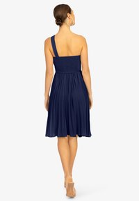 Navyblaues Kleid mit einem gerafften Oberteil, einem einzigen Schulterträger und einem knielangen, plissierten Rock. Glattes, leichtes Gewebe mit fließender Textur.