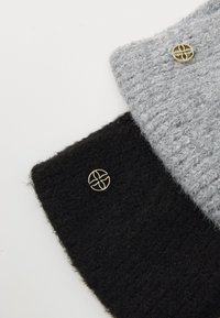 Two textured fabric swatches, one gray and one black, each with a gold circular accent. Both display a soft, knitted appearance.