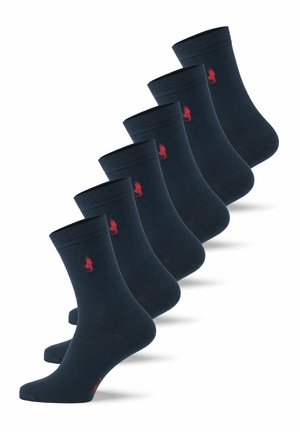 Seis pares de calcetines de tripulación azul marino con un pequeño logo bordado en rojo en el tobillo, dispuestos en diagonal sobre un fondo blanco.
