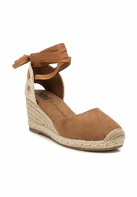 Alpargatas de cuña de ante marrón con suela de yute trenzado, con un tirante de tobillo a cuadros beige y lazos de cinta. Diseño de puntera redondeada.