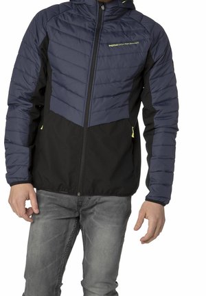 Homme portant une veste matelassée bleu marine et noire avec une fermeture éclair à l'avant, des tirettes jaunes et le logo « PROTEST HIGH PERFORMANCE » sur la poitrine.