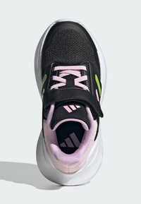 Chaussure de sport noire avec une tige en mesh texturé, des accents roses, une sangle noire et une semelle blanche. Présente trois bandes sur la semelle intérieure.