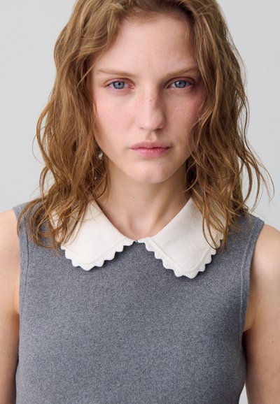 Top senza maniche grigio in maglia con collo bianco a onda e texture liscia, caratterizzato da un sottile dettaglio a coste sul tessuto.