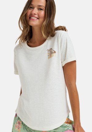 Camiseta blanca de manga corta con un cuello redondeado y una textura ligera. Presenta un diseño floral bordado en tonos dorados y marrones.