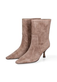 Een paar taupe suède laarzen tot halverwege het kalf met spitse neuzen en slanke kittenhakken op een witte achtergrond.