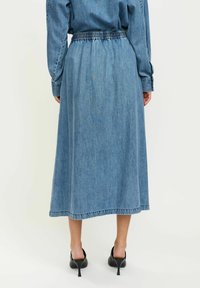 Denim krilo srednje dolžine, z nabranim elastičnim pasom, svetlo modre barve in ravno silhueto.