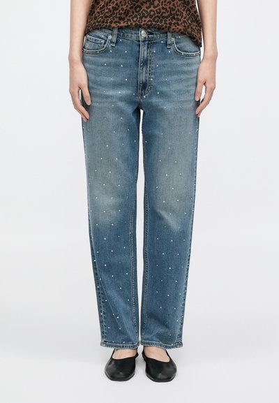 Jasnoniebieskie dżinsy o prostych nogawkach, ozdobione metalowymi ćwiekami, z pięcioma kieszeniami i zapięciem na guziki.