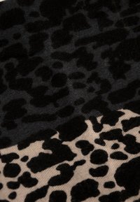 Tela negra y beige con un patrón irregular de leopardo, mostrando textura y contraste de color.