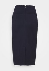 Falda lápiz ajustada en navy con cremallera trasera, de longitud a la rodilla y con detalles de costura sutiles. Confeccionada en una tela suave y texturizada.
