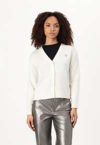 Cardigan blanc en tricot avec un col en V et une fermeture à boutons, arborant un petit logo sur la poitrine gauche et des poignets côtelés.