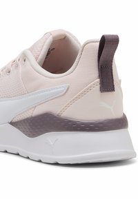 Lichtroze sneaker met bovenkant van mesh, witte accenten en een gestructureerde grijze zool. Bevat een trekband en een klein logo op de hiel.