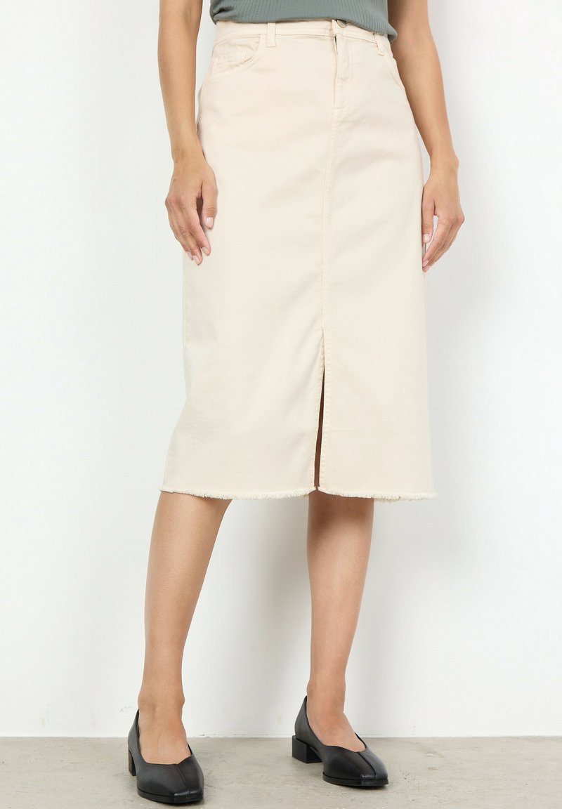 Hellbeiger Denim-Rock mit einem Schlitz vorne, rohem Saum und taillierter Passform. Kombiniert mit schwarzen Blockabsatzschuhen.