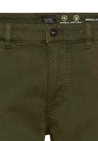 Olivgrüne Herrenhosen mit Knopfverschluss, Gürtelschlaufen und mit Etiketten versehenen Taschen, einschließlich einer Sicherheitstasche. Hergestellt aus hoch elastischem Stoff.
