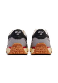 Graue und schwarze Sneaker mit einer strukturierten Oberseite, einem Logo-Detail an der Rückseite, kontrastierenden roten Akzenten und einer gemusterten Gummisohle.