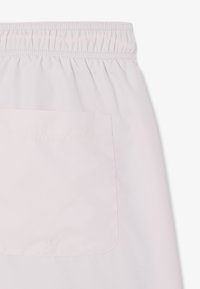 Gonna rosa chiaro con elastico in vita e una tasca rettangolare sul lato. Tessuto liscio, resistente alle pieghe e con finitura opaca.